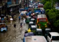 People wading through floodwaters in Dhaka after record rainfall during the Bangladesh Flood 2026, causing widespread flooding, transport disruption, and loss of lives.