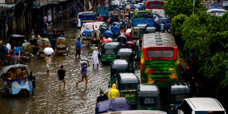 People wading through floodwaters in Dhaka after record rainfall during the Bangladesh Flood 2026, causing widespread flooding, transport disruption, and loss of lives.