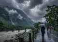 South Bengal Rain Forecast showing dark monsoon clouds, heavy rainfall over North Bengal hills and Dooars, with people using umbrellas amid continuous rain and strong winds.