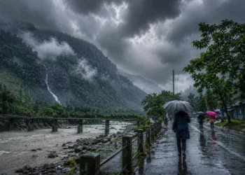 South Bengal Rain Forecast showing dark monsoon clouds, heavy rainfall over North Bengal hills and Dooars, with people using umbrellas amid continuous rain and strong winds.