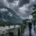 South Bengal Rain Forecast showing dark monsoon clouds, heavy rainfall over North Bengal hills and Dooars, with people using umbrellas amid continuous rain and strong winds.