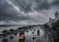 West Bengal Heavy Rain Alert showing dark monsoon clouds over Kolkata with heavy rainfall as the IMD issues warnings for South Bengal and North Bengal districts.